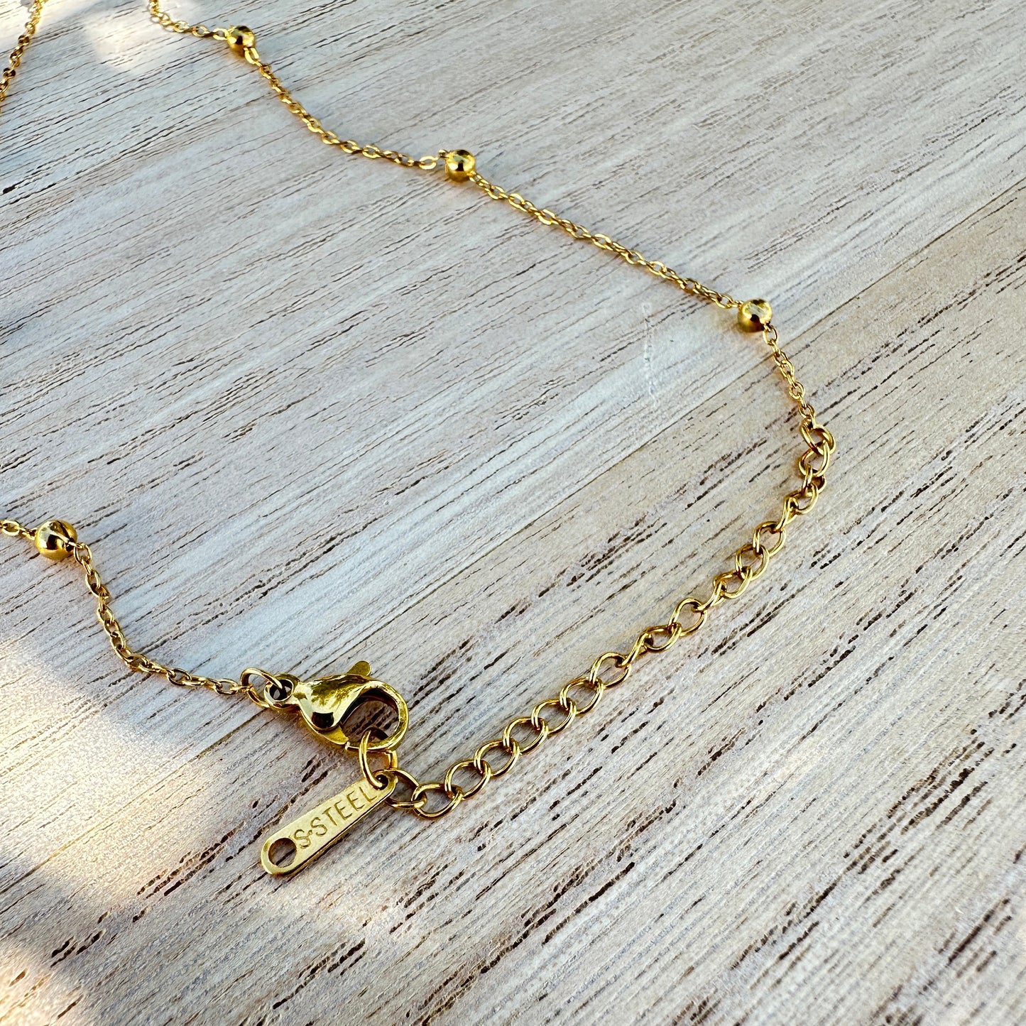 Detailaufnahme des Verschlusses einer goldfarbenen Edelstahl Halskette mit Verlängerungskette und Edelstahl Anhänger.