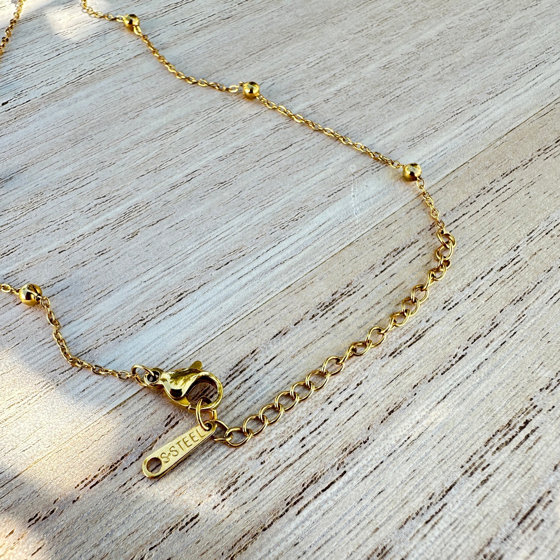 Detailaufnahme des Verschlusses einer goldfarbenen Edelstahl Halskette mit Verlängerungskette und Edelstahl Anhänger.