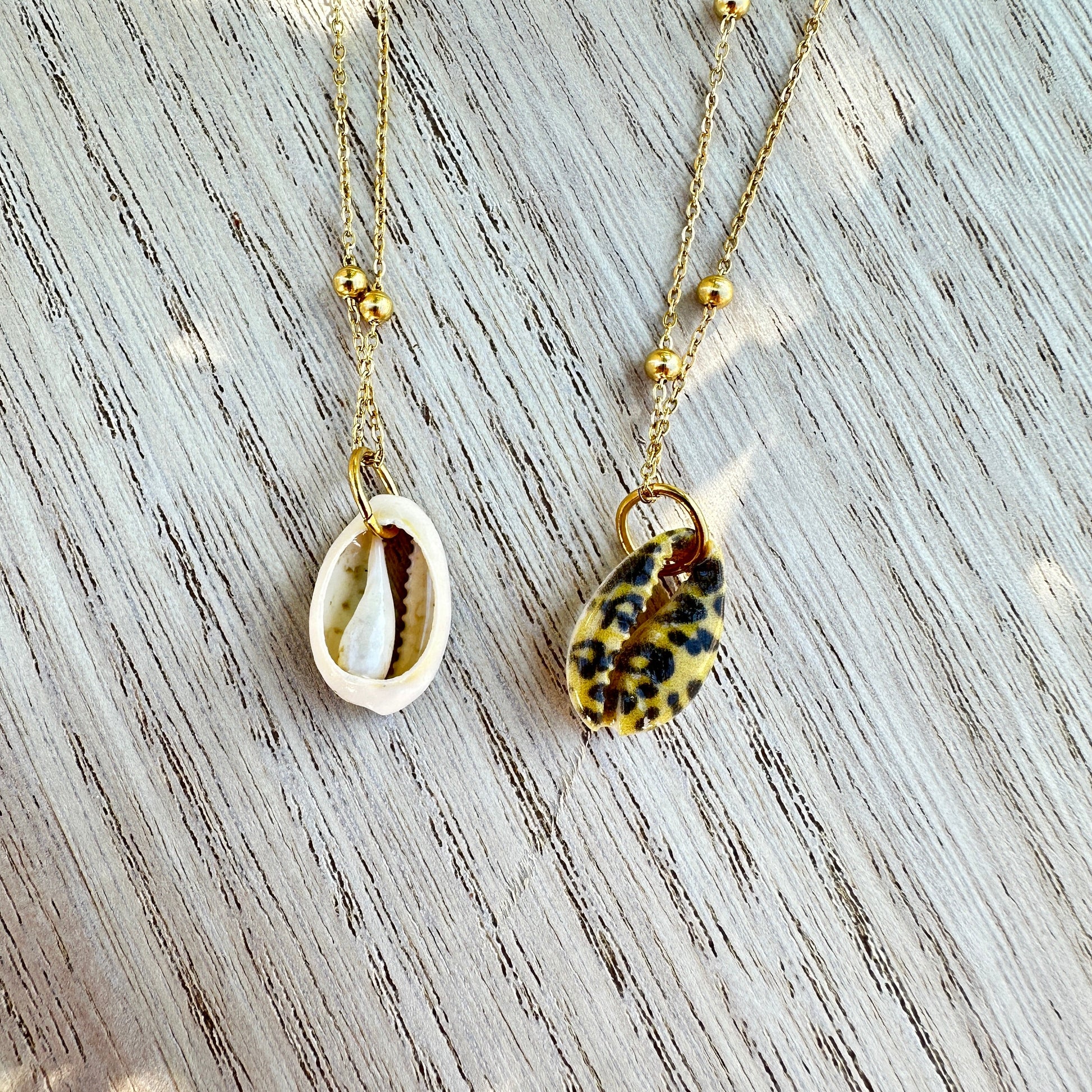 Rückseite einer Kaurimuschel im Leo-Design an goldener Edelstahlkette.