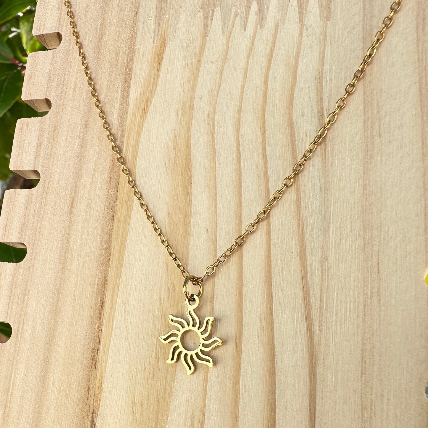 Detailaufnahme einer vergoldeten Edelstahl Halskette mit Sonnenanhänger.