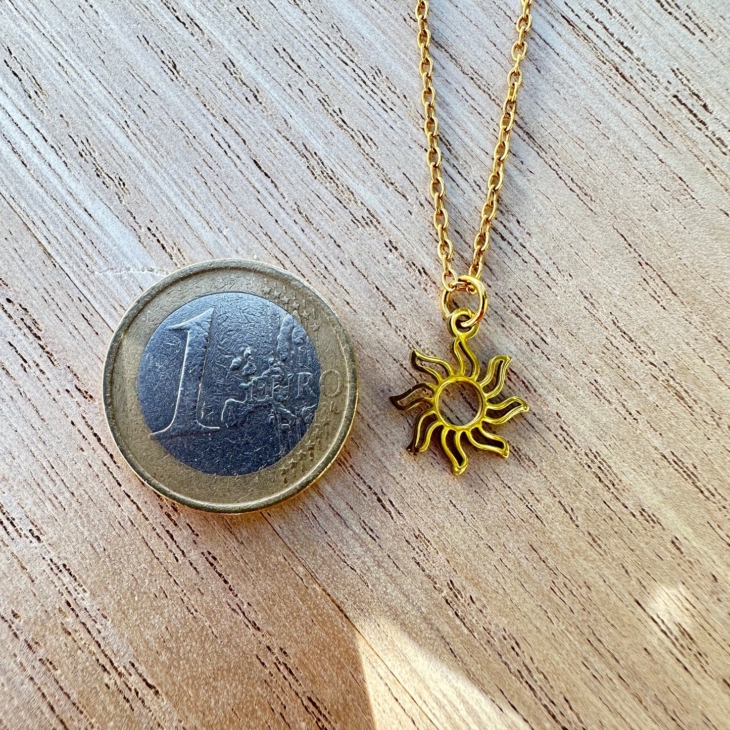 Sonnenanhänger Edelstahlhalskette im Größenvergleich mit einem 1Euro Stück