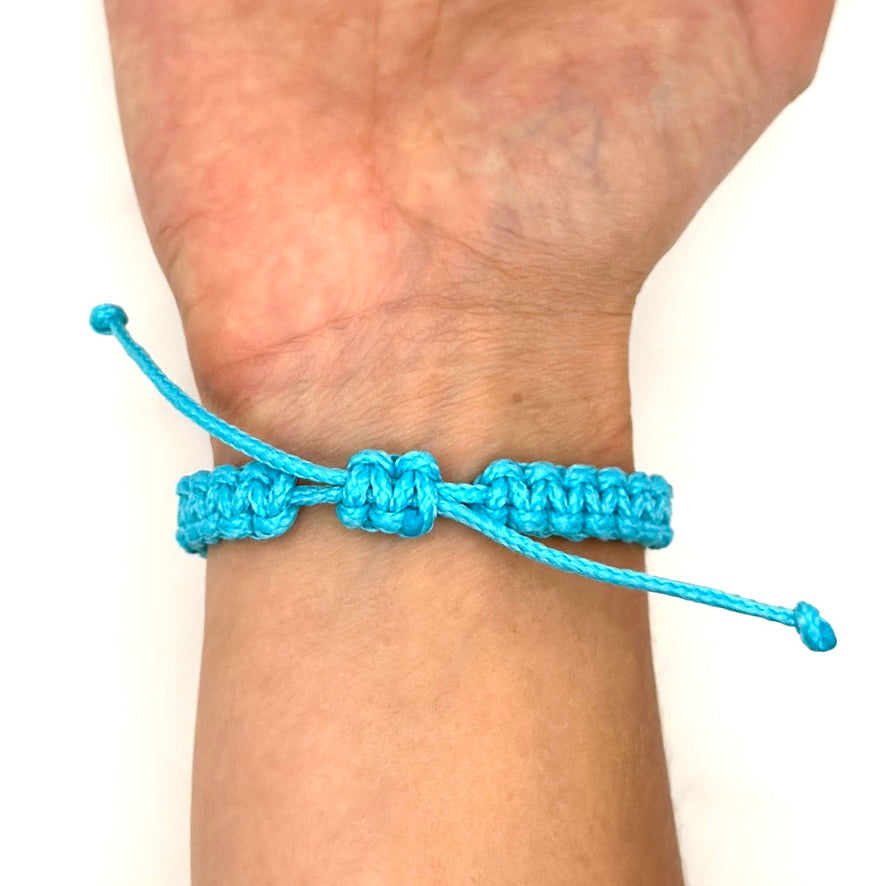 Handgelenk mit türkisen Segltau-Armband. Das Foto zeigt die Rückseite mit dem Schiebeknoten. Dadruch kann das Armband in seiner Länge verändert werden