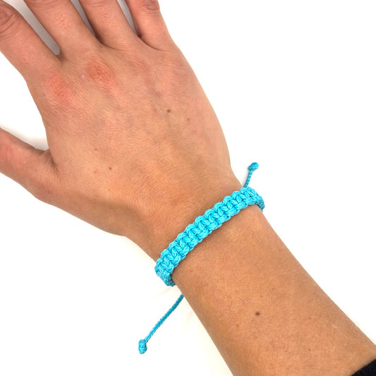 Handgelenk mit türkisfarbenem Armband. Geknüpft mit dem Kreuzknoten