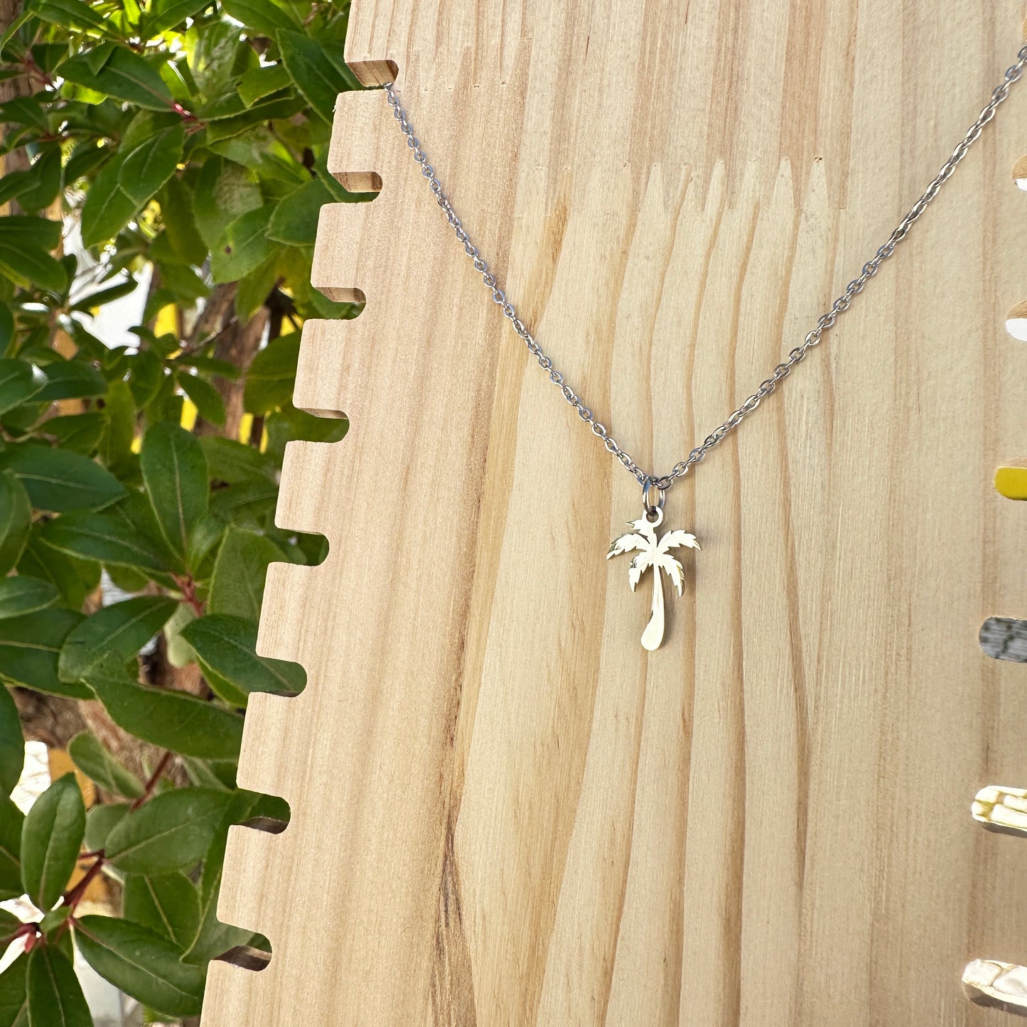 Silberne Edelstahl Kette mit Palmenanhänger auf Holzplatte fotografiert