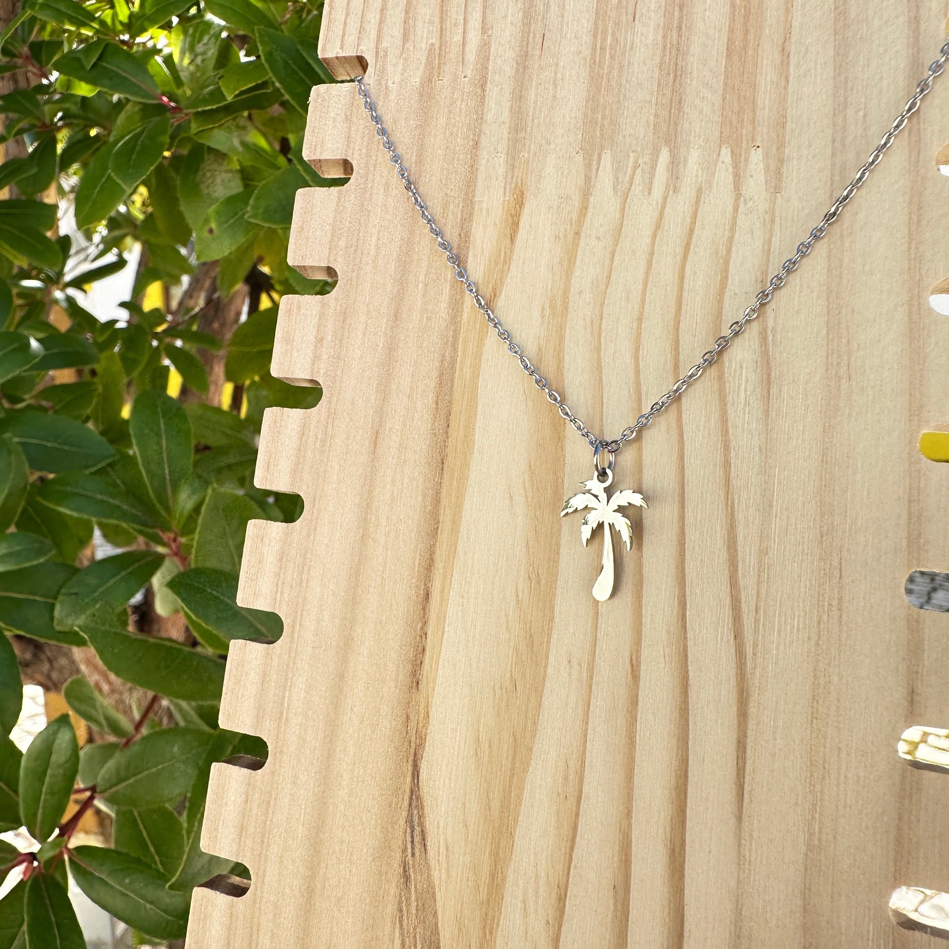 Silberne Edelstahl Kette mit Palmenanhänger auf Holzplatte fotografiert