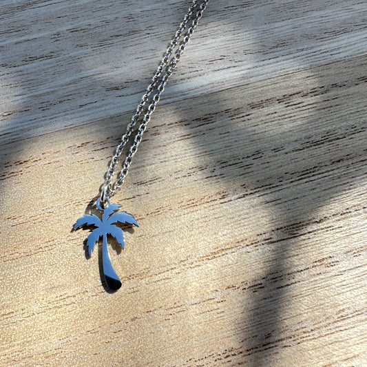 Silberne Edelstahl Kette mit Palmenanhänger auf Holzuntergrund