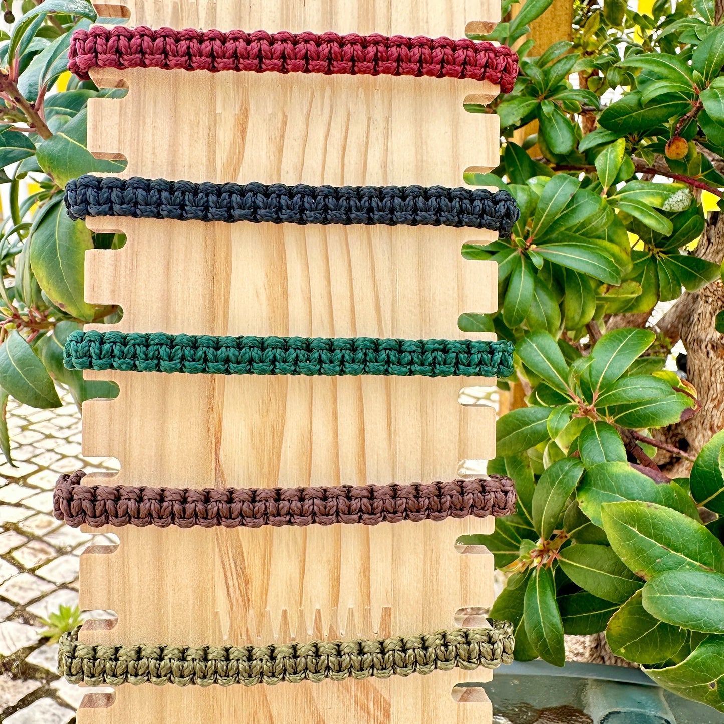 Hölzernes Display mit 5 handgeknüpften Segeltau Armbändern in verschiedenen Farben.