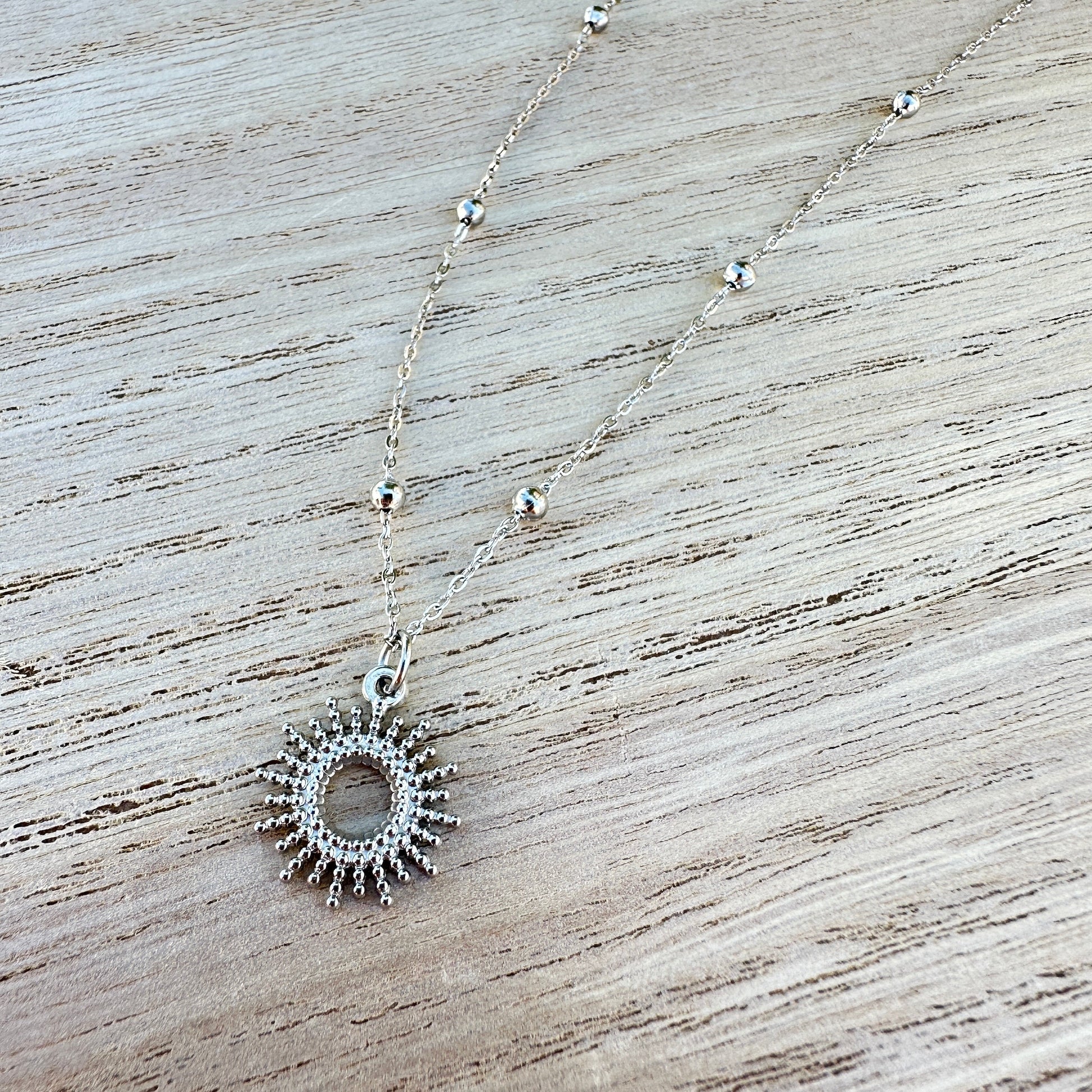 Silberne Sonnen Kette aus Edelstahl mit Kugeldetails auf Holzuntergrund