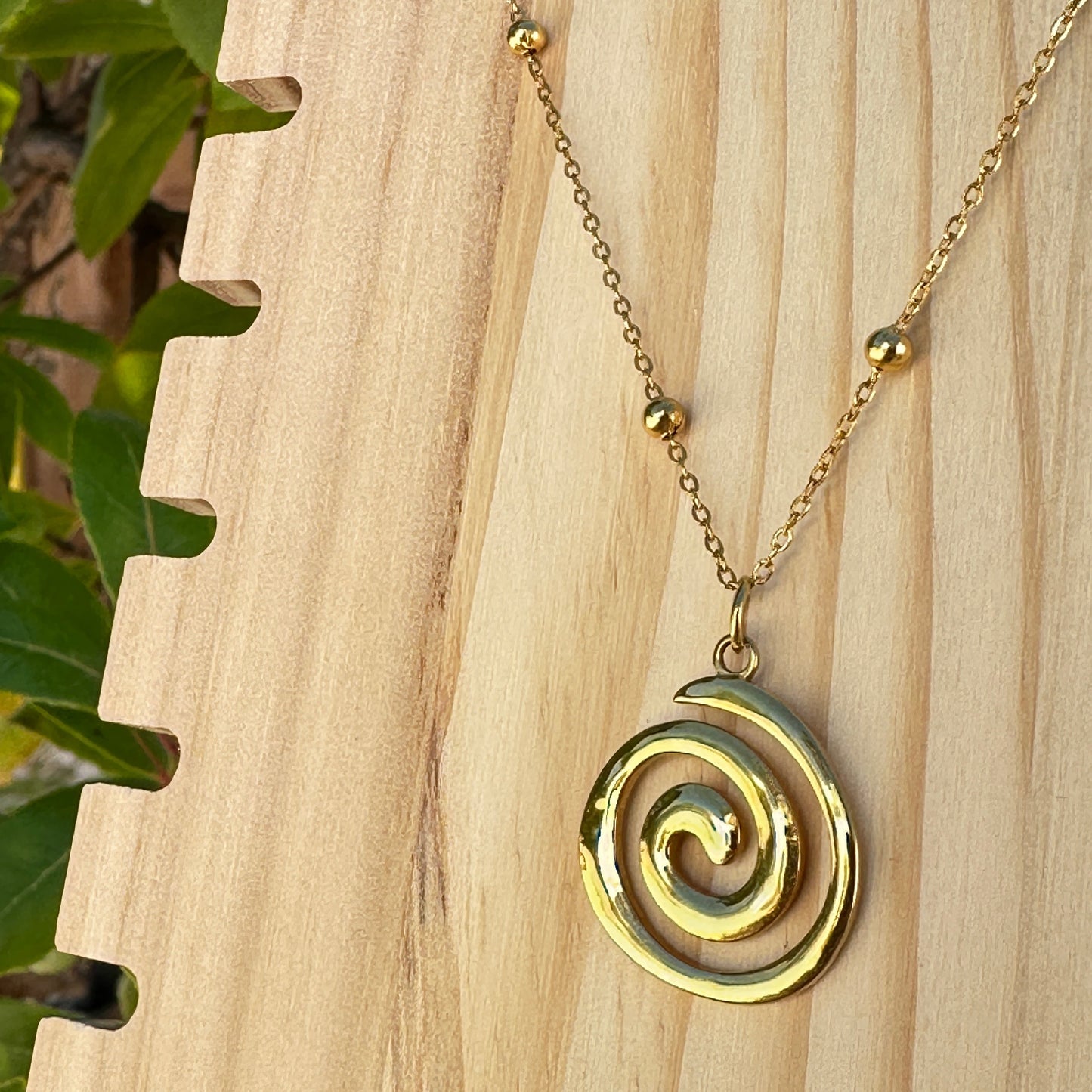Detailaufnahme des goldenen Spiral-Anhängers aus Edelstahl mit Kugelkette